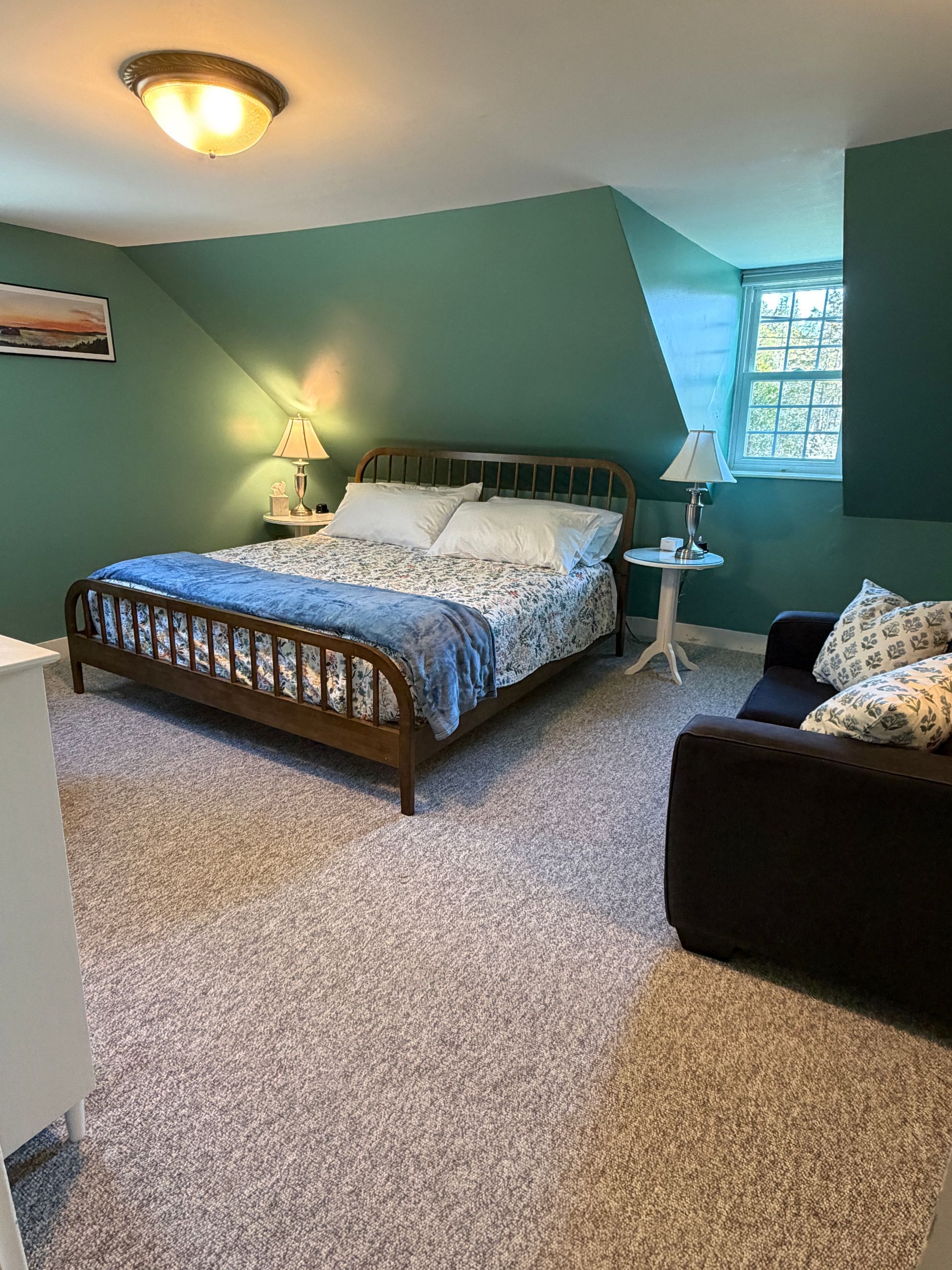 Bedroom with teal walls, a bed with floral quilt, and a daybed.