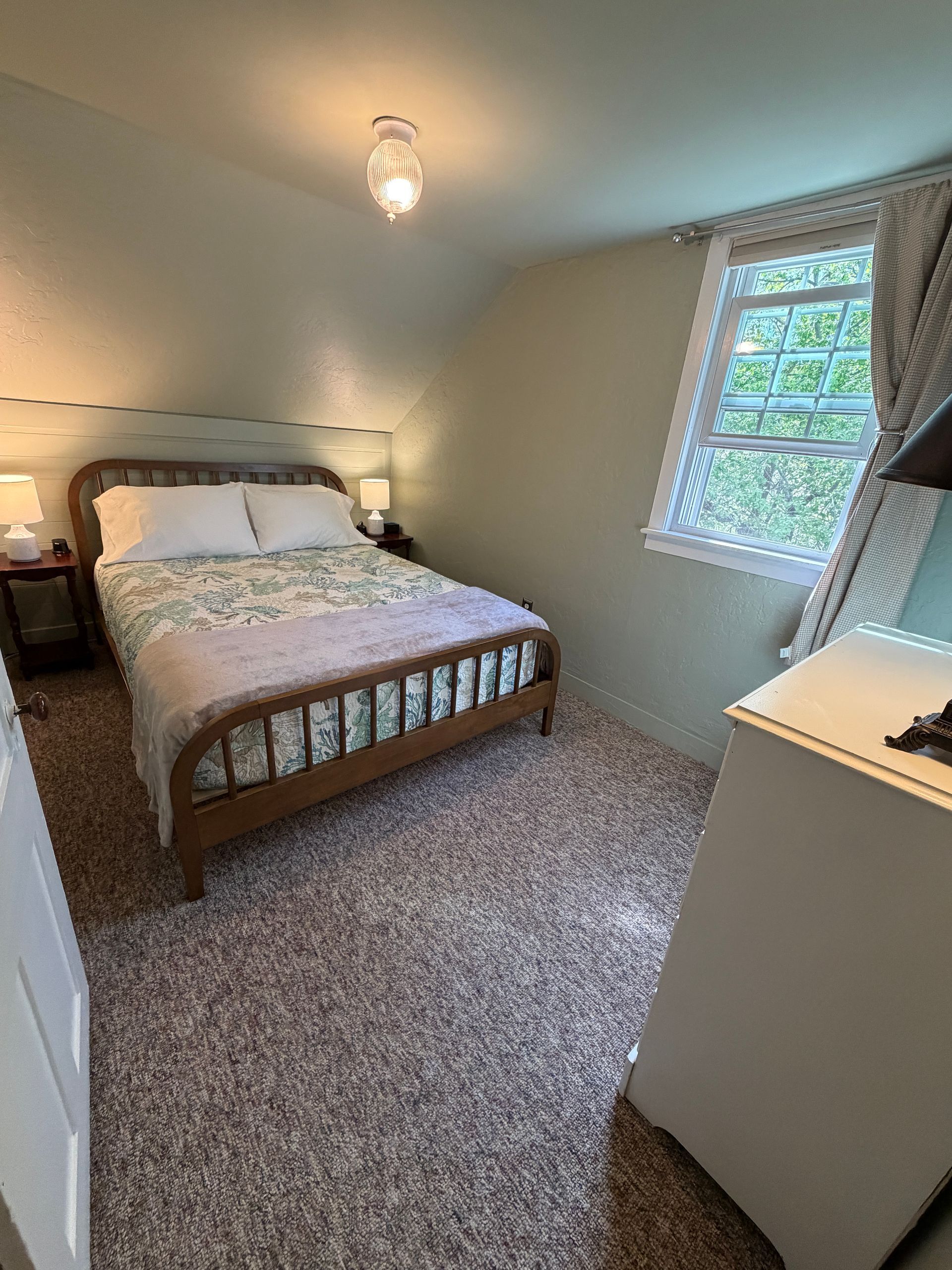 Bedroom with a bed, armchair, window with blinds, and green
 walls.