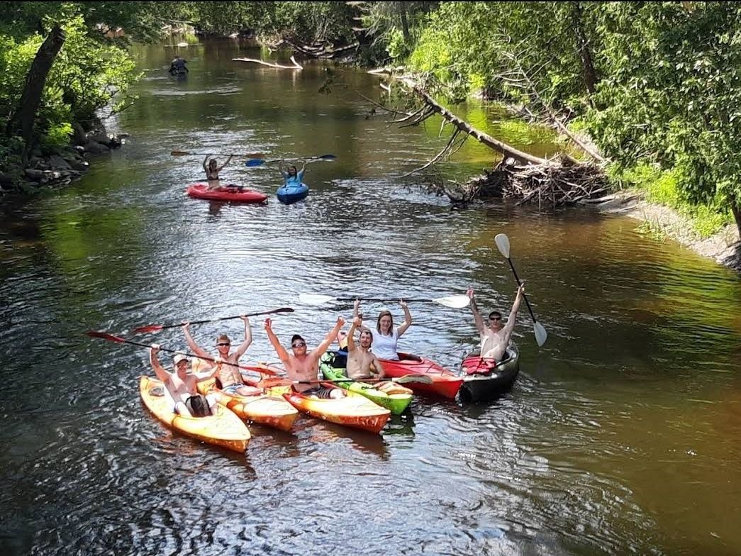 A group of people are rowing kayaks down a river.