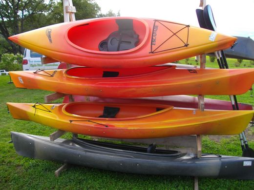 A bunch of kayaks are stacked on top of each other
