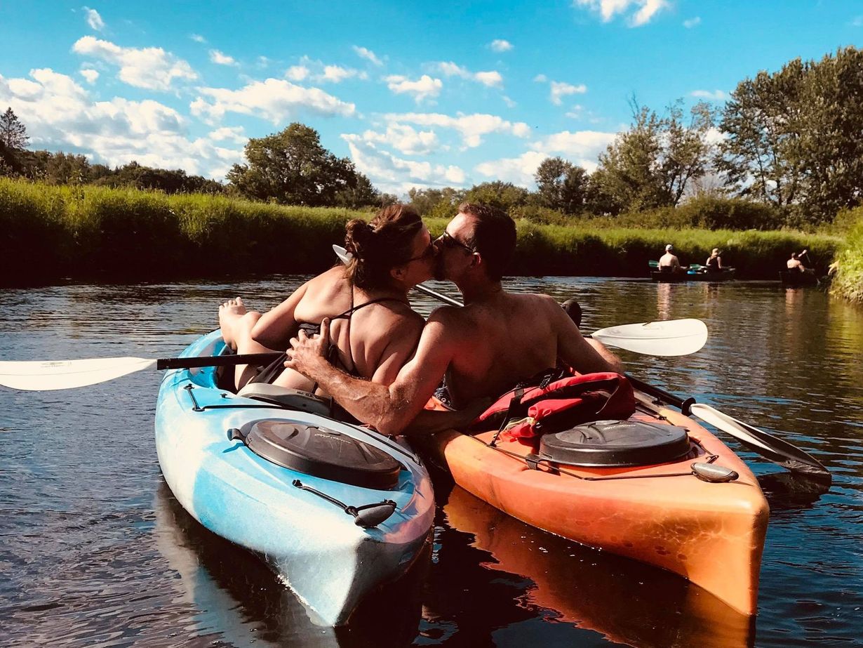 A man and a woman are kissing in a kayak on a river.