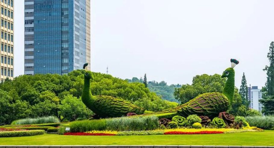 Topiary peacock in a landscaped park with tall glass office buildings in the background