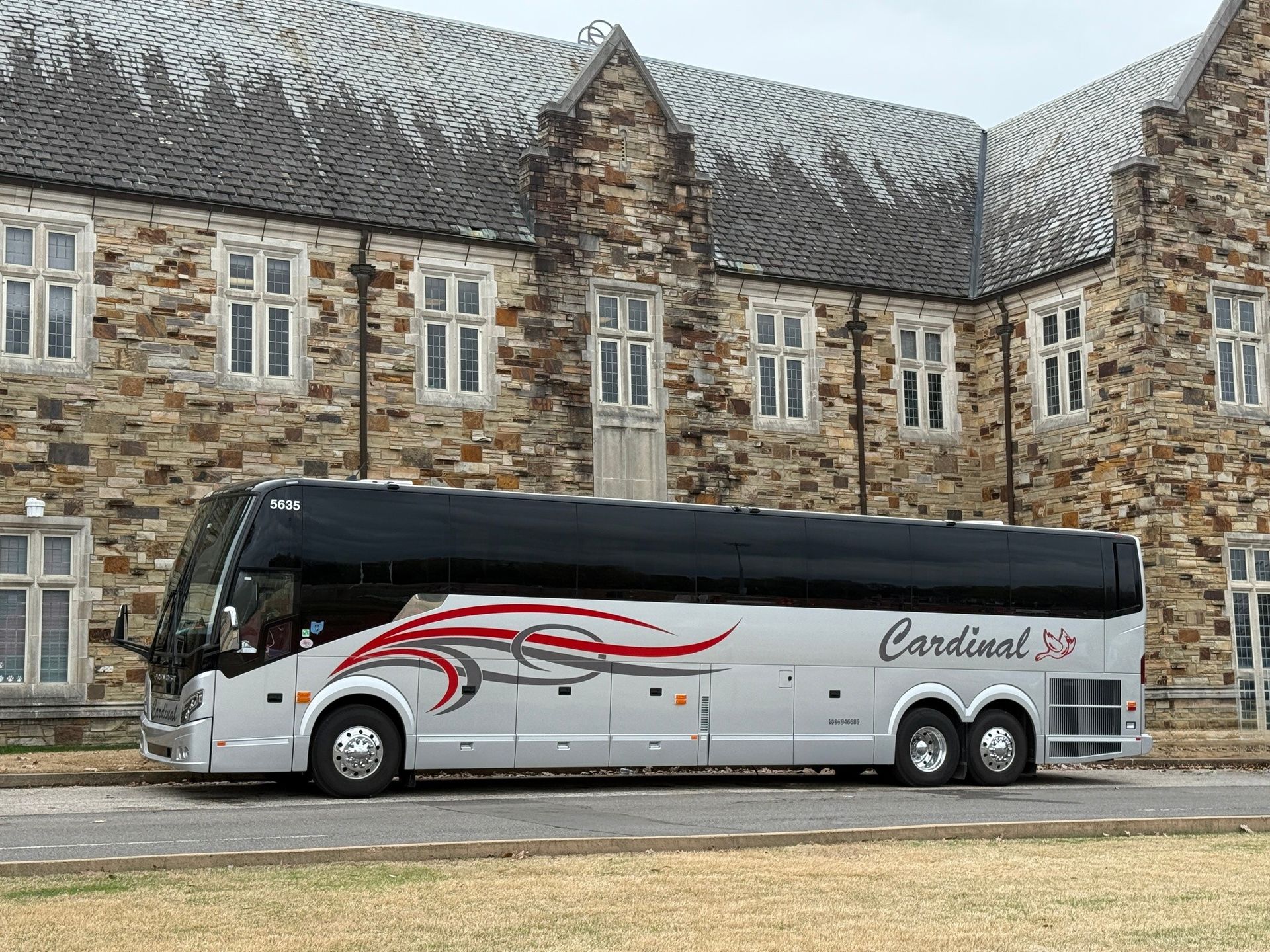 Charter bus parked in front of a stone academic building on a college campus. Charter bus parked in front of a stone academic building on a college campus.