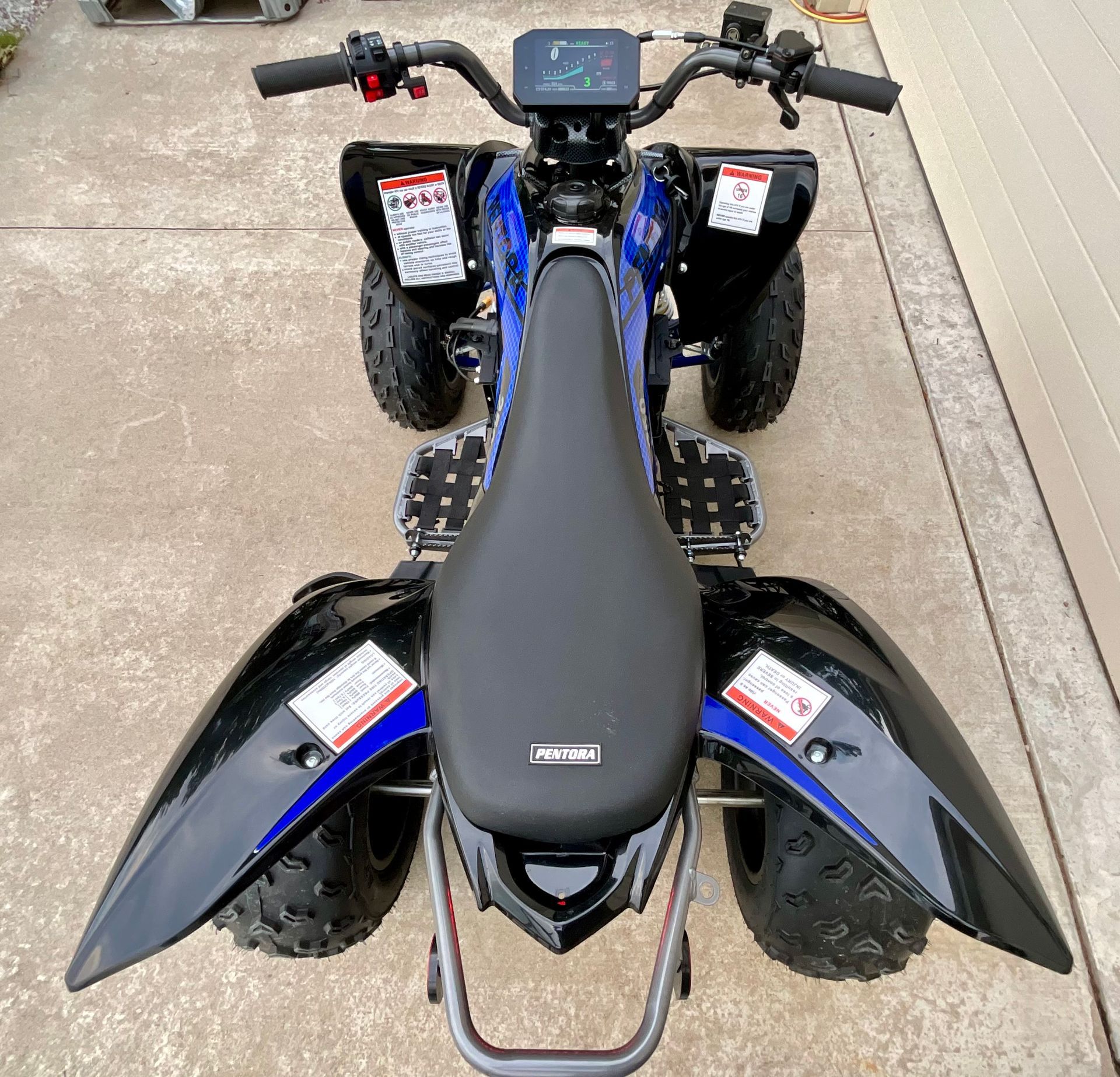 Black-and-blue ATV parked on concrete, viewed from above.