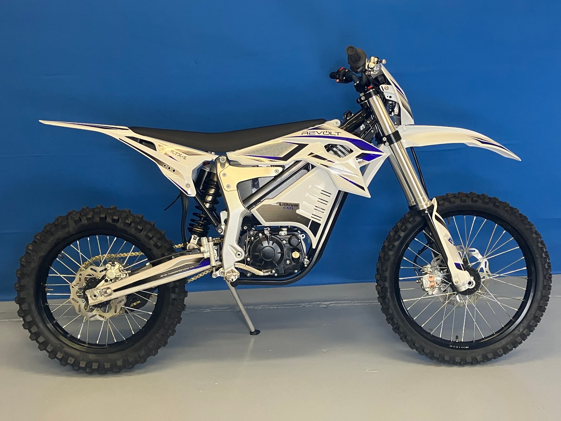 White off-road dirt bike with black wheels on a studio blue background