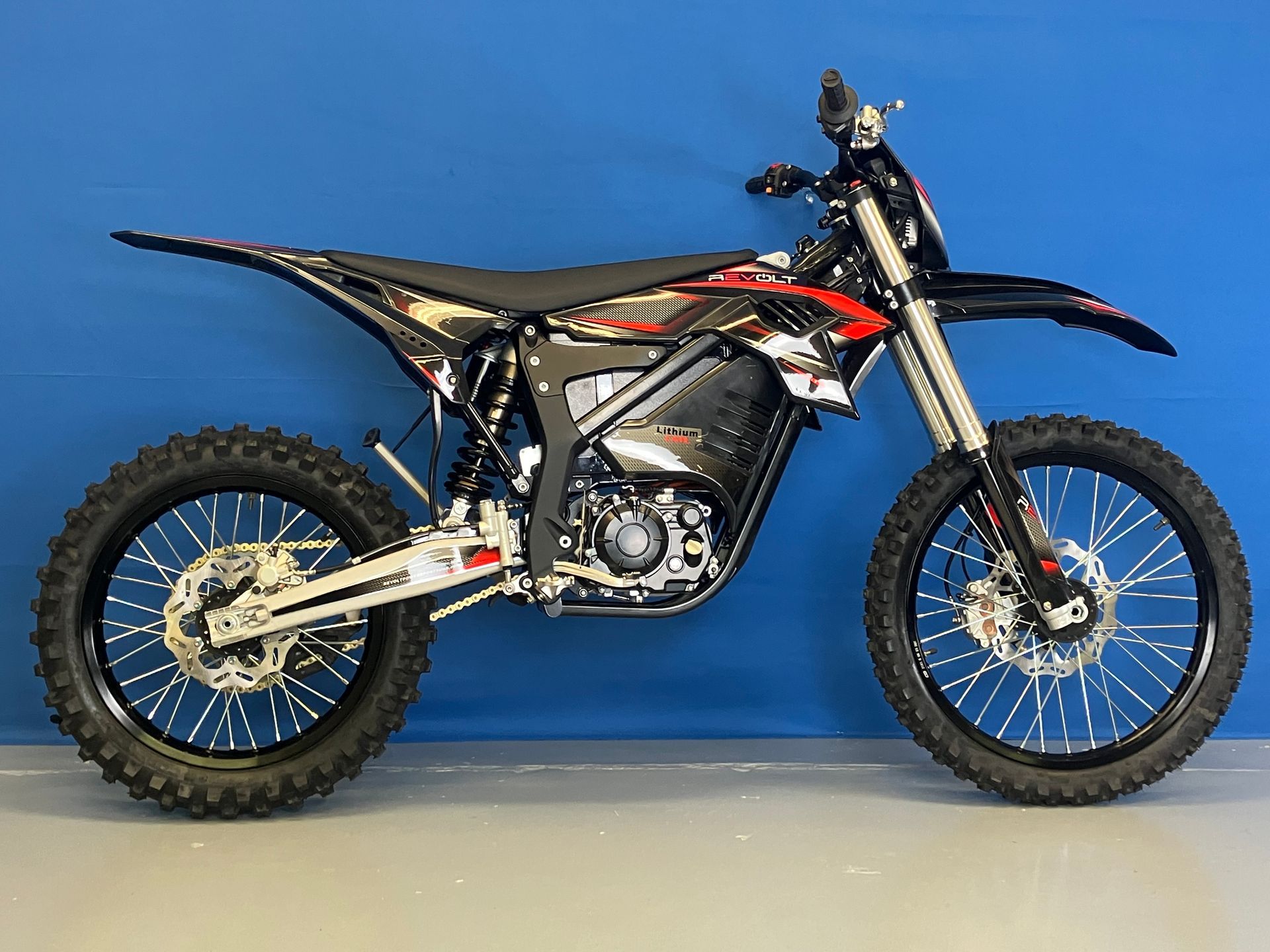 Black and red dirt bike in profile against a blue background