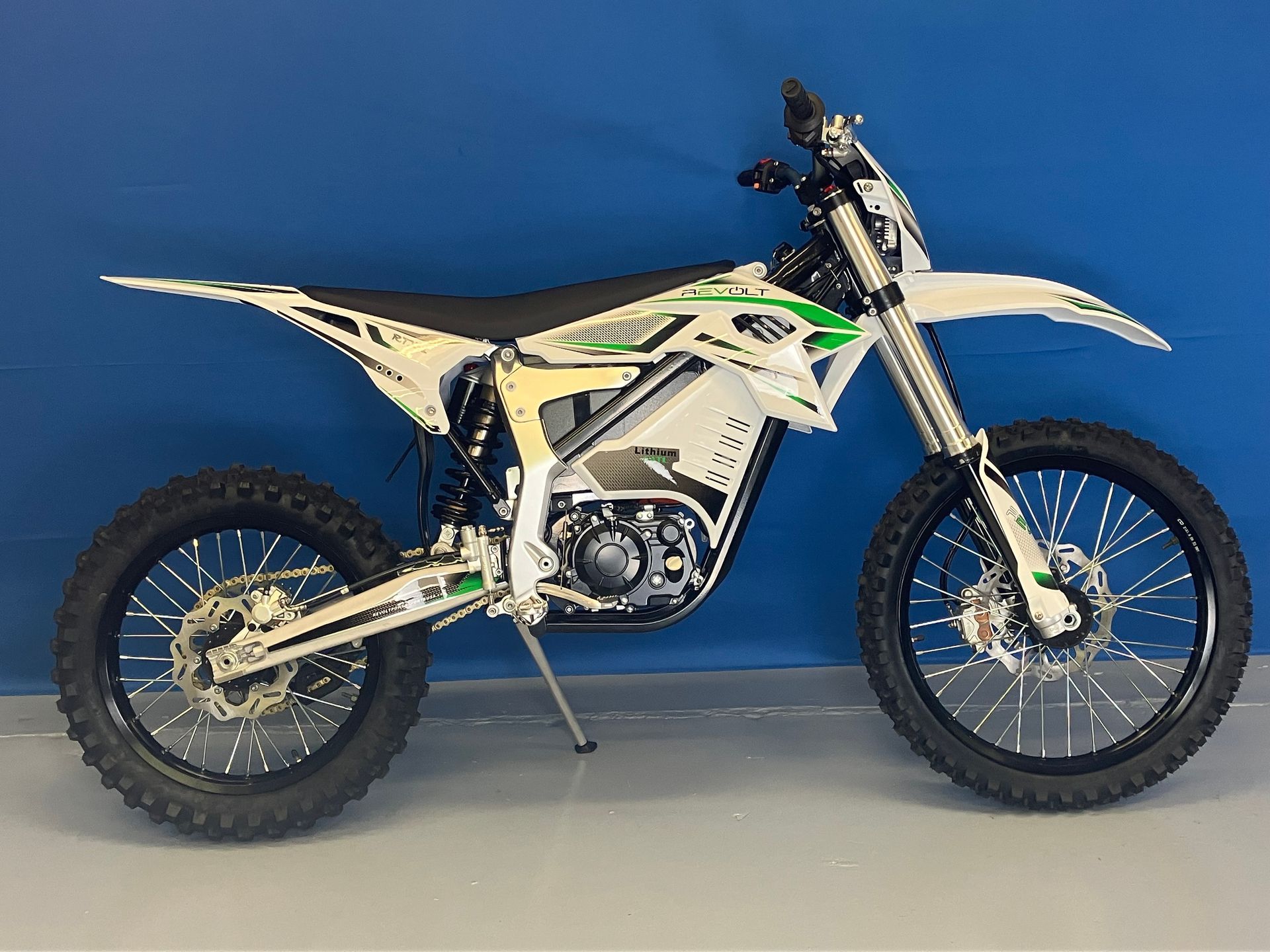 White dirt bike with black wheels and green accents on a blue backdrop