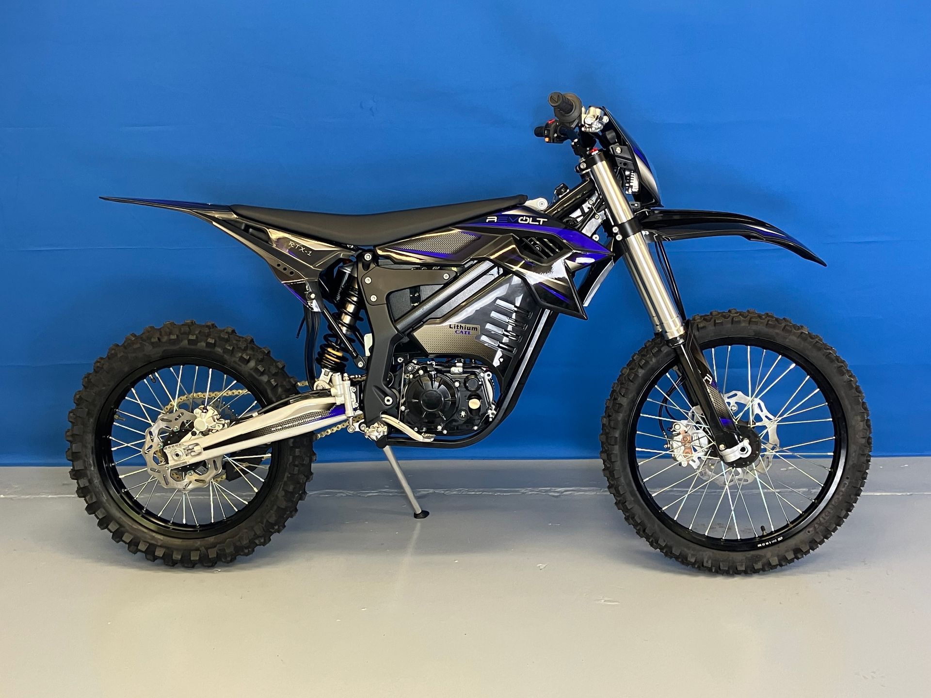 Black dirt bike on a stand against a blue backdrop
