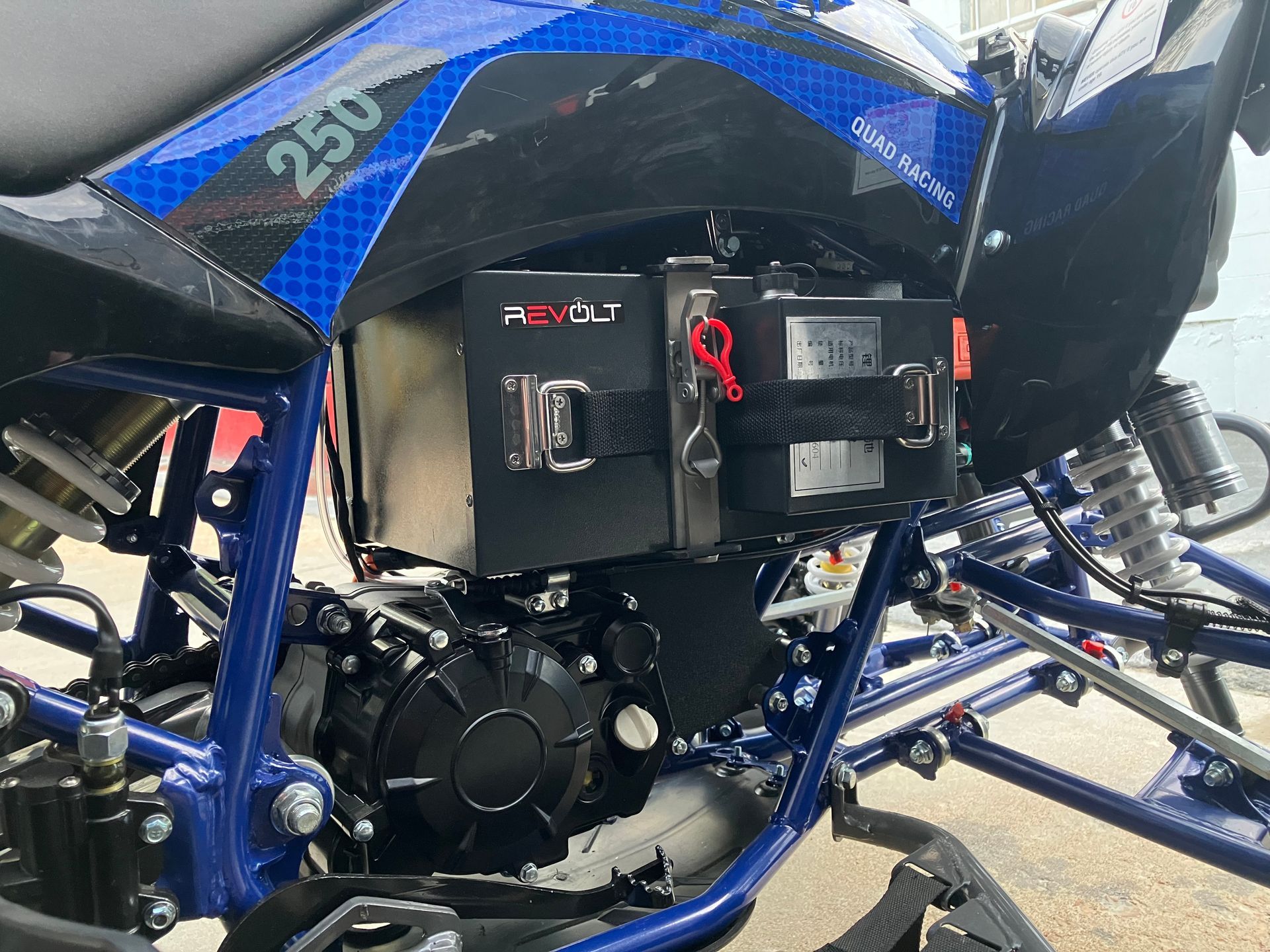 Blue off-road vehicle close-up showing a black side storage box mounted on a blue frame.