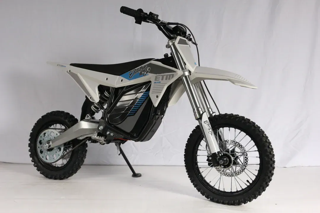 White and black dirt bike on a stand, side view on a plain white background