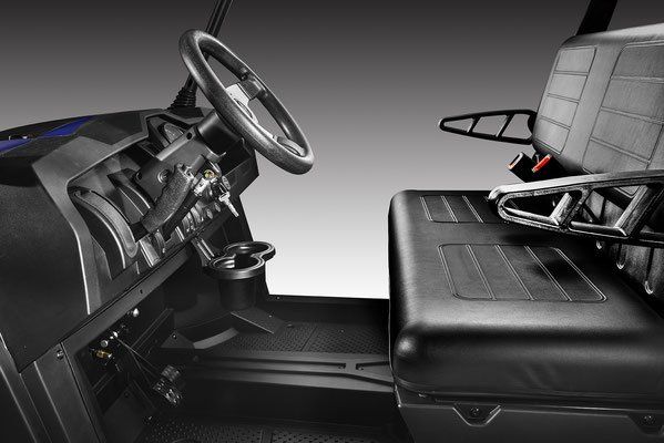 Car interior showing the driver’s seat, steering wheel, and a black rear seat with folding armrest.