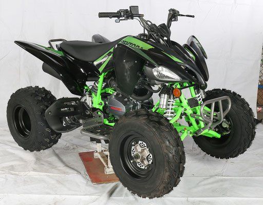 A green and black atv is sitting on a white surface.