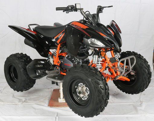 Black and orange four-wheeler ATV with oversized tires on a white studio backdrop