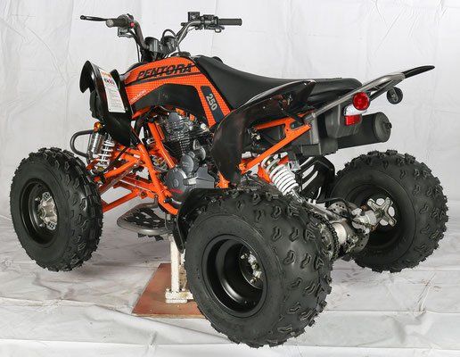 Orange and black four-wheeled ATV with large off-road tires on a studio backdrop