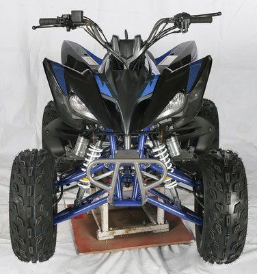 Front view of a black and blue ATV with knobby tires and silver suspension on a stand