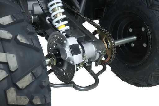 Close-up of a bicycle rear drivetrain with chain, sprocket, suspension spring, and large knobby tire