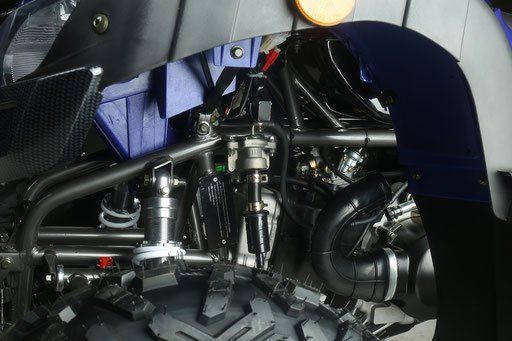 Close-up of a vehicle engine bay with metallic suspension and mechanical components under a blue body panel