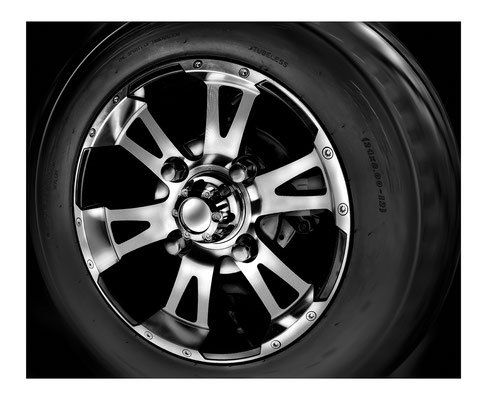 Close-up of a silver car wheel rim and tire on a black background