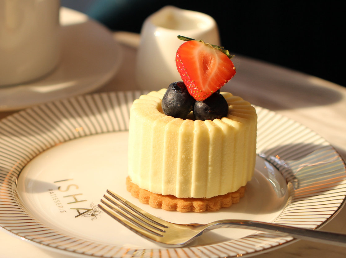 A person is pouring milk on a piece of cake on a plate.