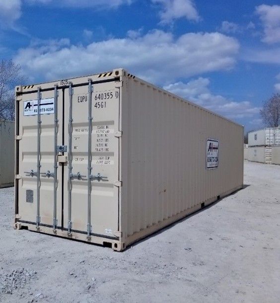 White shipping container on a snowy lot under a blue sky with clouds.