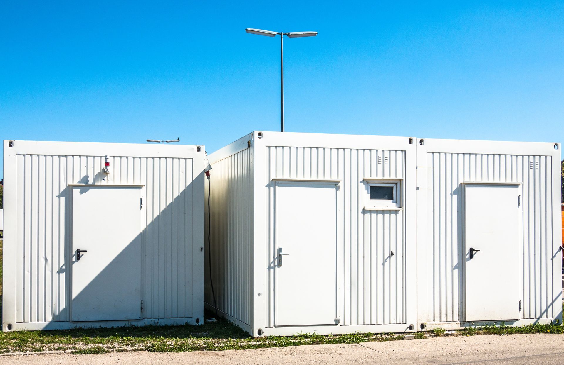 Three white mobile storage containers for rental with the blue sky in the background. Three white mobile storage containers for rental with the blue sky in the background.