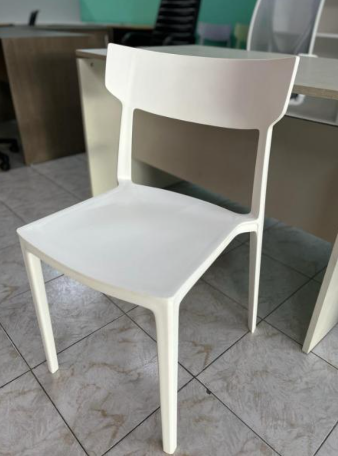 Silla moderna blanca con respaldo curvo sobre un suelo de baldosas en el interior.