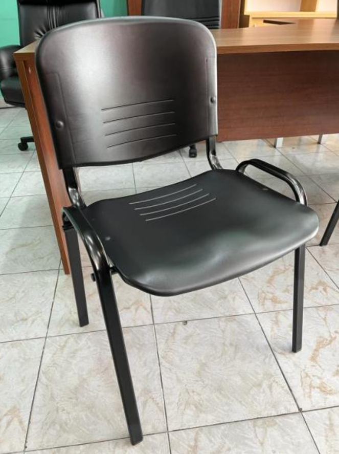 Silla de oficina negra con patas de metal sobre un suelo de baldosas en una habitación.