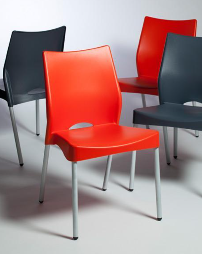 Sillas modernas en negro, rojo y gris dispuestas en grupo sobre un suelo claro.