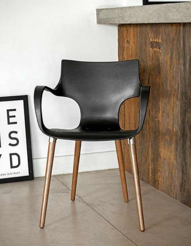 Silla moderna negra con patas de madera junto a un mostrador de madera y un cuadro enmarcado en la pared.