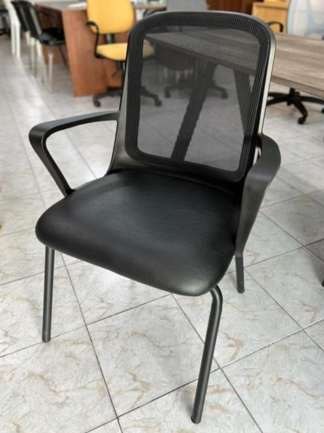 Silla de oficina de malla negra con asiento y reposabrazos acolchados sobre un suelo de baldosas.