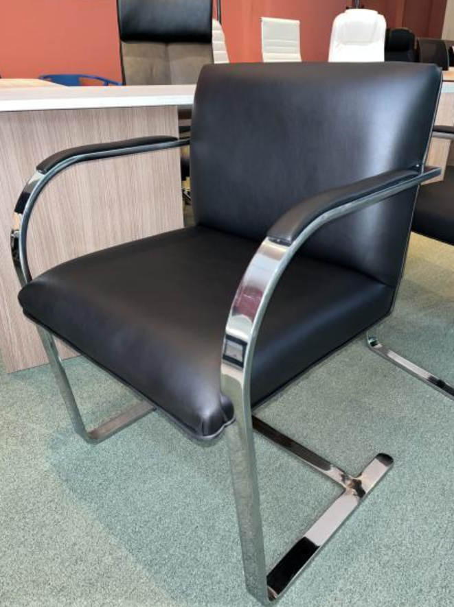 Silla tapizada en negro con brazos cromados en una sala de espera de oficina.