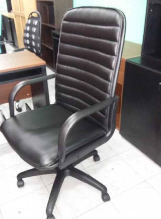 Silla de oficina negra acolchada con reposabrazos y ruedas en un entorno de oficina.