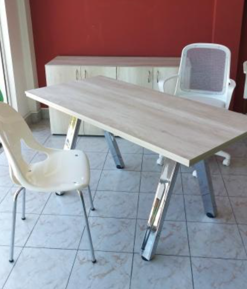 Sillas blancas alrededor de una mesa de madera clara en una habitación alicatada con una pared roja.