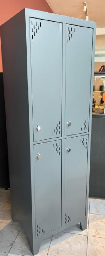 Taquilla alta de metal gris con cuatro puertas y rejillas de ventilación en forma de diamante en un entorno interior.