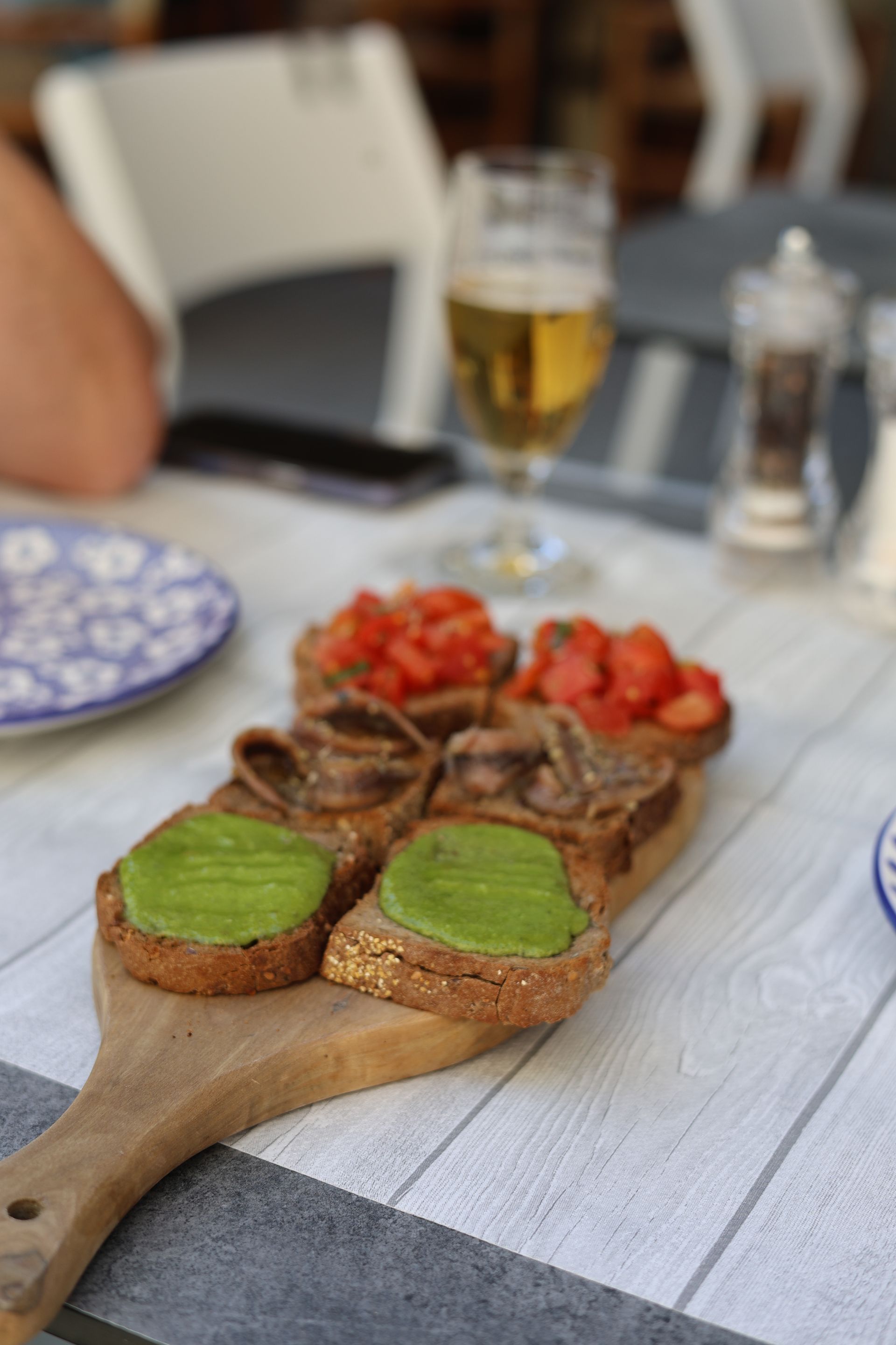 Mani che reggono una fetta di pizza sopra un piatto con una pizza vegetariana su un tavolo