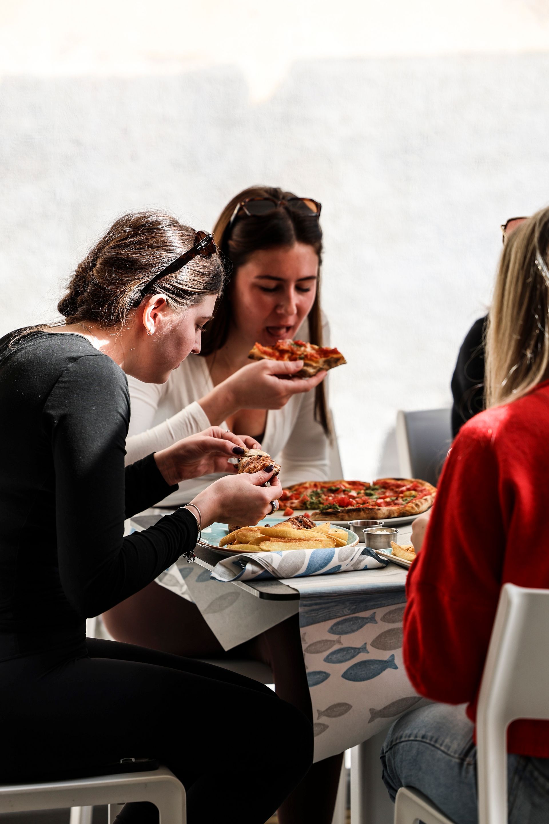 Persone che mangiano la pizza insieme a un tavolo in un ambiente interno informale.