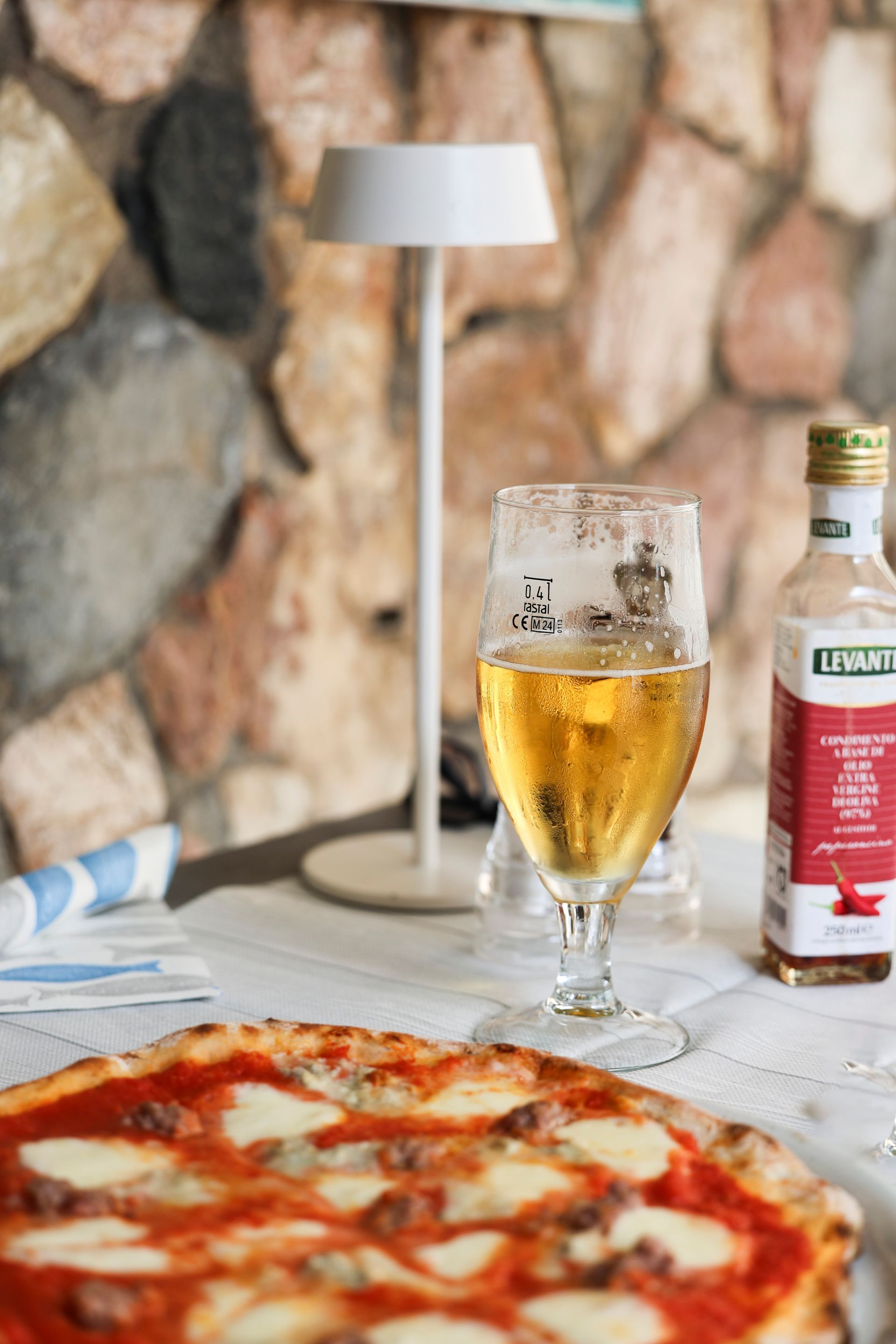 Pizza, un bicchiere di birra e una bottiglia di bibita su un tavolo nell'accogliente atmosfera di un ristorante.