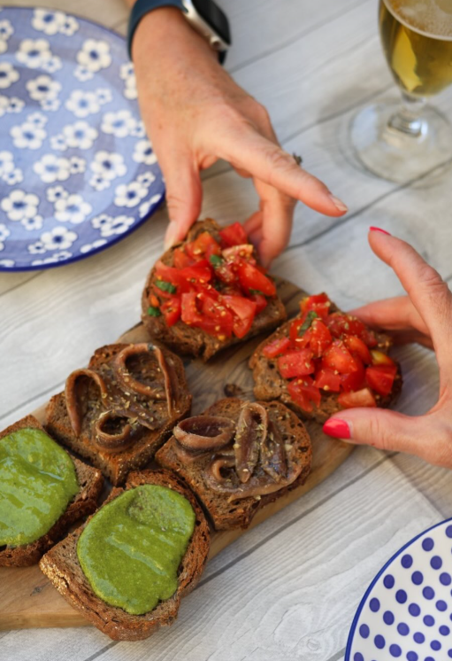 Bruschette assortite su un piatto di legno, condite con pesto verde, pomodori e funghi.