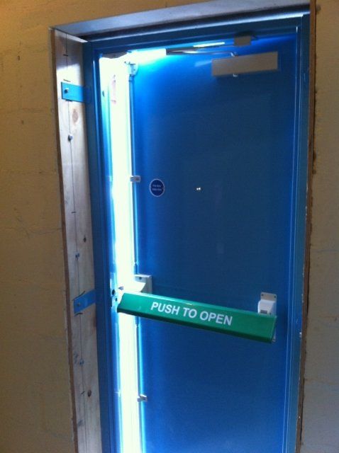 A blue door with a green handle that says push to open