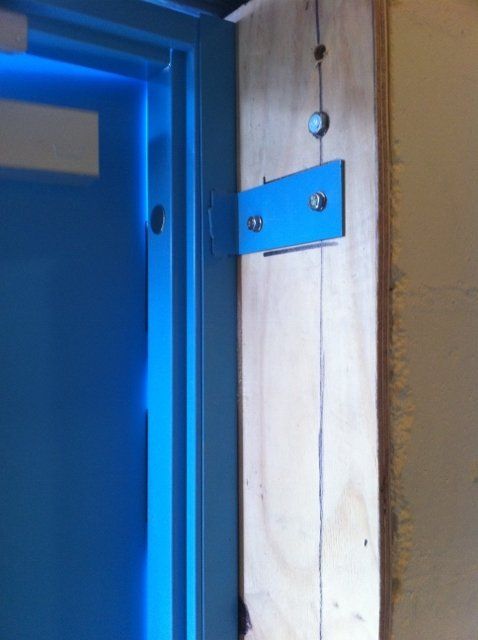 A blue door is hanging on a wooden wall