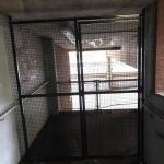 There is a cage in the middle of a hallway.