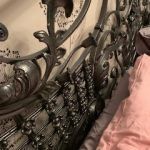 A woman in a pink dress is sitting on a chair with a wrought iron railing.