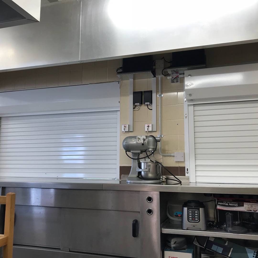A kitchen with stainless steel appliances and white shutters.