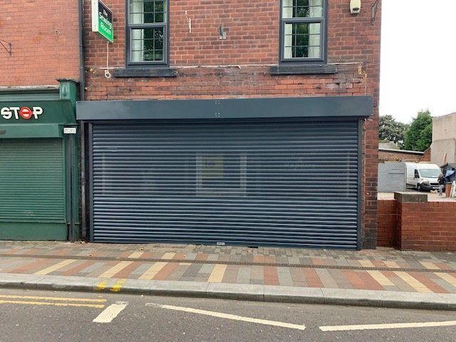 A brick building with a black shutter on the side of it.