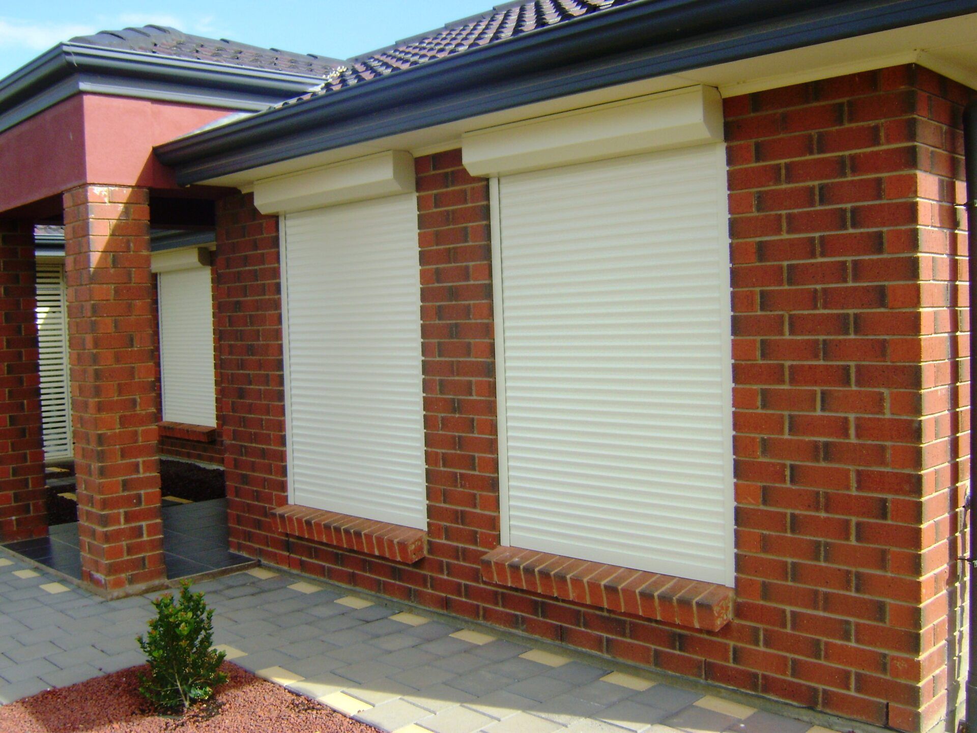 A brick building with white roller shutters on the windows