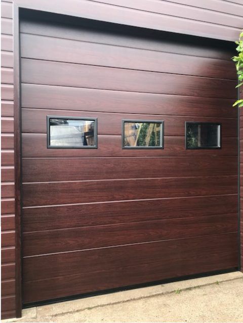 A dark brown, horizontal-paneled garage door with a row of three small, rectangular windows.