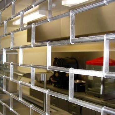 A silver metal security grille covers a food service counter with equipment and a red appliance visible behind it.