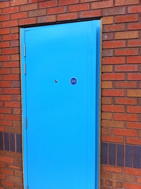 A blue door is in a brick wall