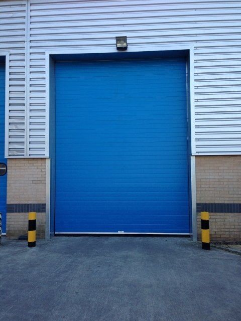 A blue garage door with yellow poles in front of it