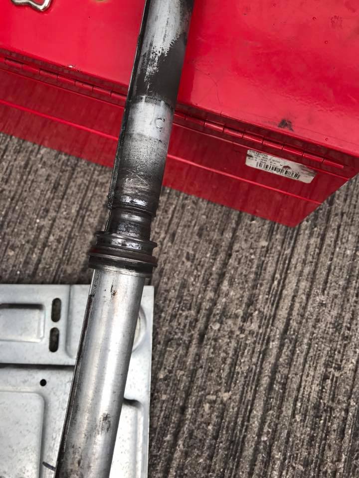 A metal pipe is sitting on the ground next to a red toolbox.